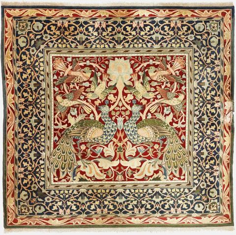 Carpet. A dense pattern created in tones of ruby red, sage green, muted blue, shell pink, and cream white shows two peacocks and six birds in a central panel surrounded by a wide band of leafy vines.