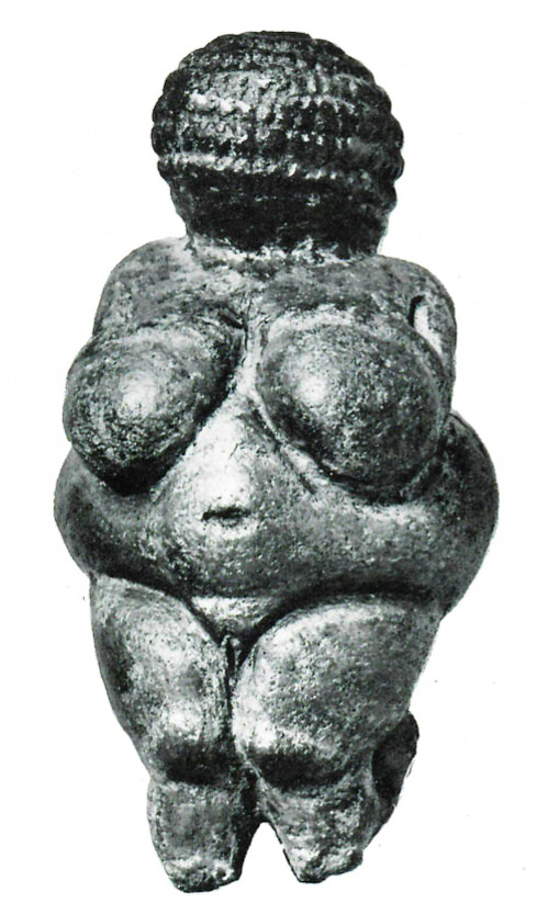 Sculpture. Reproduced in black and white, this statuette has a bulbous, textured orb for a head, bulging breasts and belly, a deep navel, defined pubis, and legs that taper or have been broken.