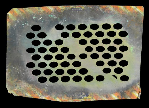 Stencil. The original yellow and orange diagonal stripes of this roughly rectangular of cardboard are largely covered with grey and muted lime-green paint. The cardboard has been perforated to create a mostly uniform grid of wide ovals, though the pattern is broken down the centre.