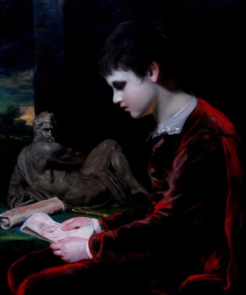 Painting. Shown from the lap up, a young boy with smooth, noticeably pale skin sits looking at a drawing, facing our left in profile. His black hair blends into the dark background. Light on his red velvet suit creates a nearly electric scarlet outline.