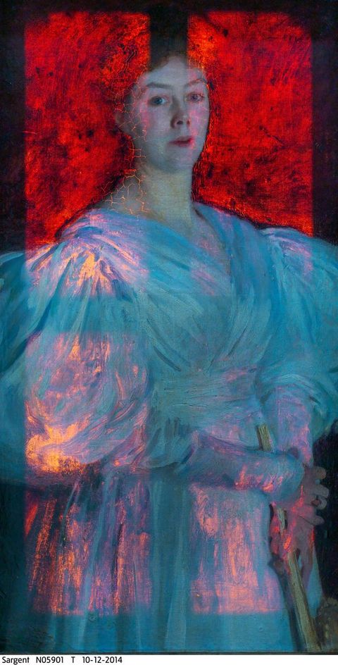 Colour photograph. A portrait shows a woman from the hips up, wearing a puffed sleeve dress. The canvas is lit from behind so her white dress looks like fiery opals. The background behind her is luminous red.