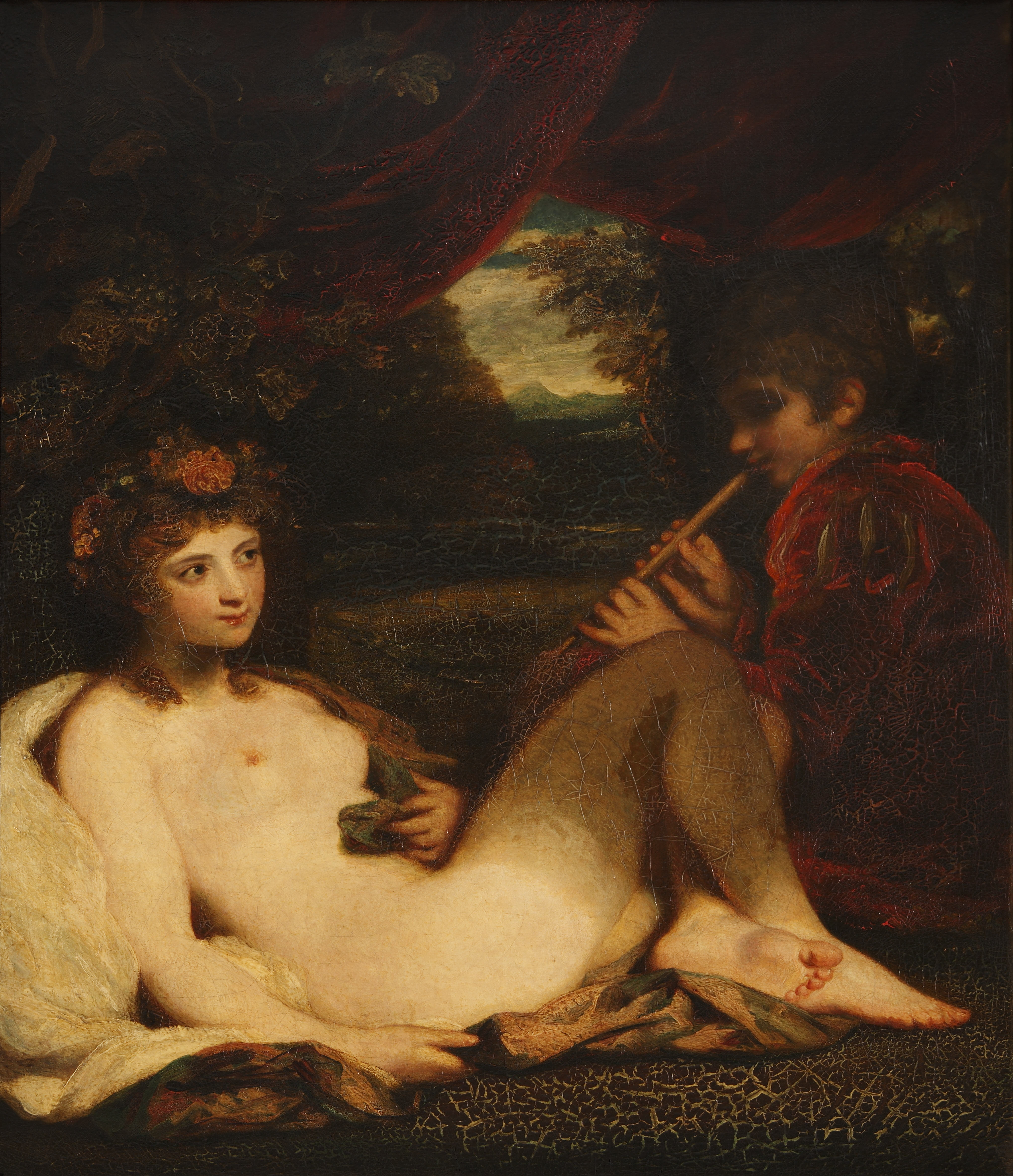 Painting. A nude, pale-skinned woman reclining against a white cloth in a forest smiles slightly at a boy playing a pipe. Her knees are bent and her feet tucked into the lower right corner of this vertical composition. The boy wears a red velvet jacket with slashed sleeves. A shadowy forest opens beyond the pair.