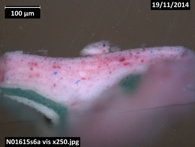 Colour photograph. A microscopic cross section of paint shows a layer of white paint covered first by green and then pink. Text in the upper corners read, “100 µm” and “19/11/2014”. A label in the lower left reads, “N01615s6a vis x 250.jpeg”.