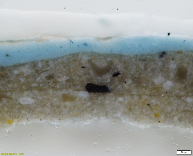 Colour photograph. In this microscopic cross section of paint, two layers of parchment white is flecked with bright white and yellow. The uppermost layer is bright blue. Text in the lower left corner reads, “Magnification: 40x”, and in the lower right, “20µm”.