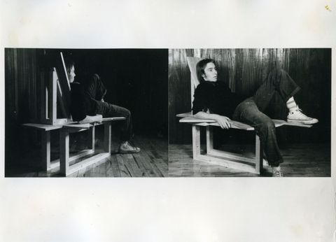 Two black and white photographs. Each photograph shows a pale-skinned man lying back on a wooden sculpture resembling a deconstructed chair. A projecting plank of wood gives him a place to prop up his foot. In one photograph, we look on from behind the man, and in the other, we see his face and body in profile.