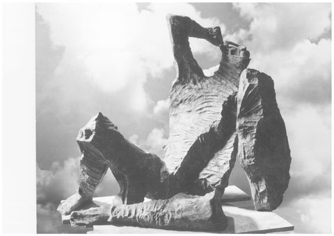 Sculpture. Black and white photograph of a freestanding, bronze, abstracted human form half reclining with a shield in one hand and the other raised to the head. The surface of the bronze is rough as if extra material had been chiselled off.