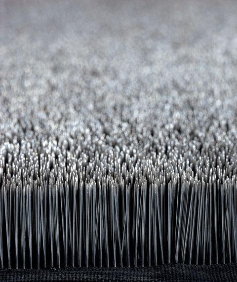 Sculpture. Detail view of rows of countless pins, set so their points face upwards. The surface created by the pinpoints shimmers silver.