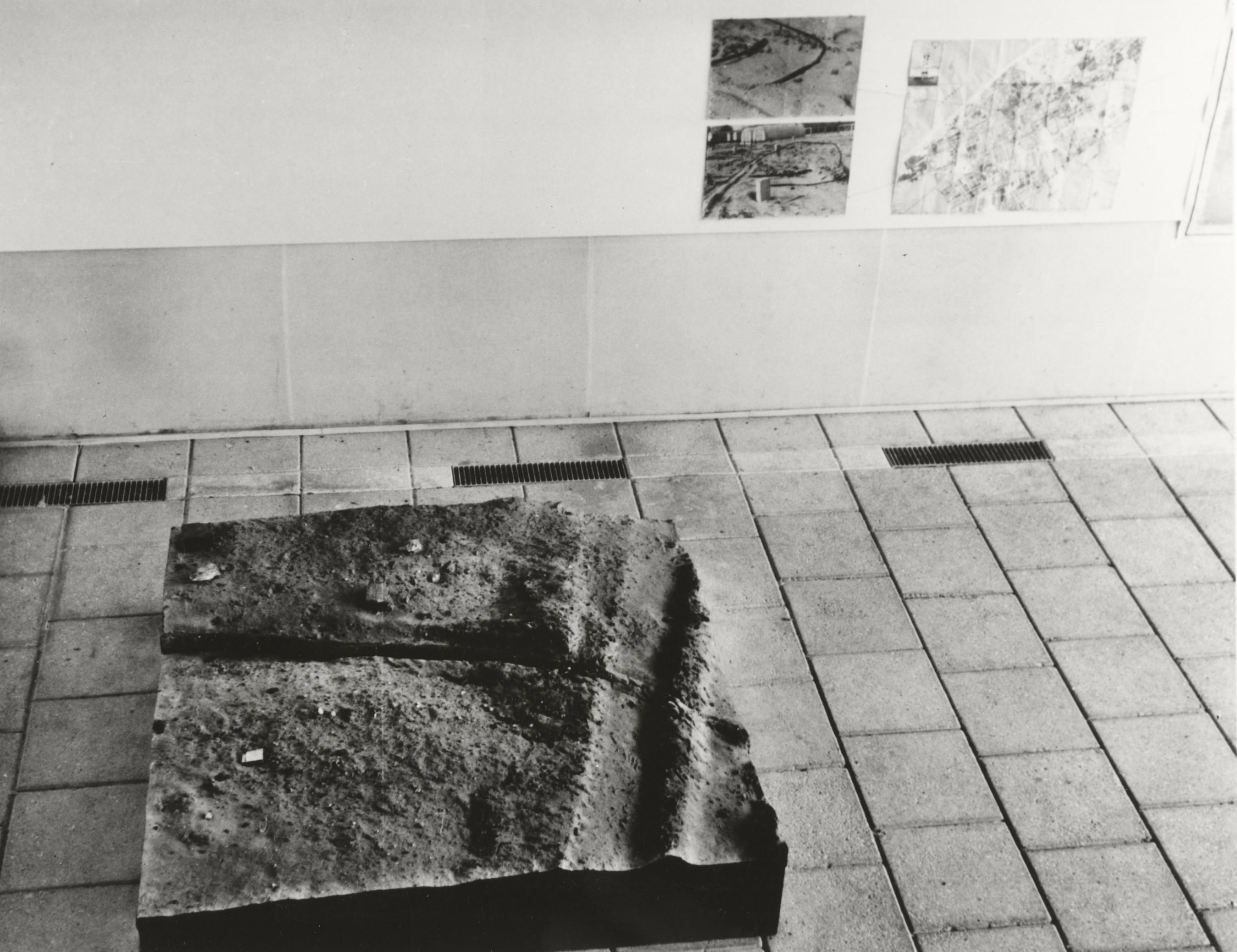 Installation photograph. Black and white photograph shows a panel of resin that had been cast over a square area of dirt.