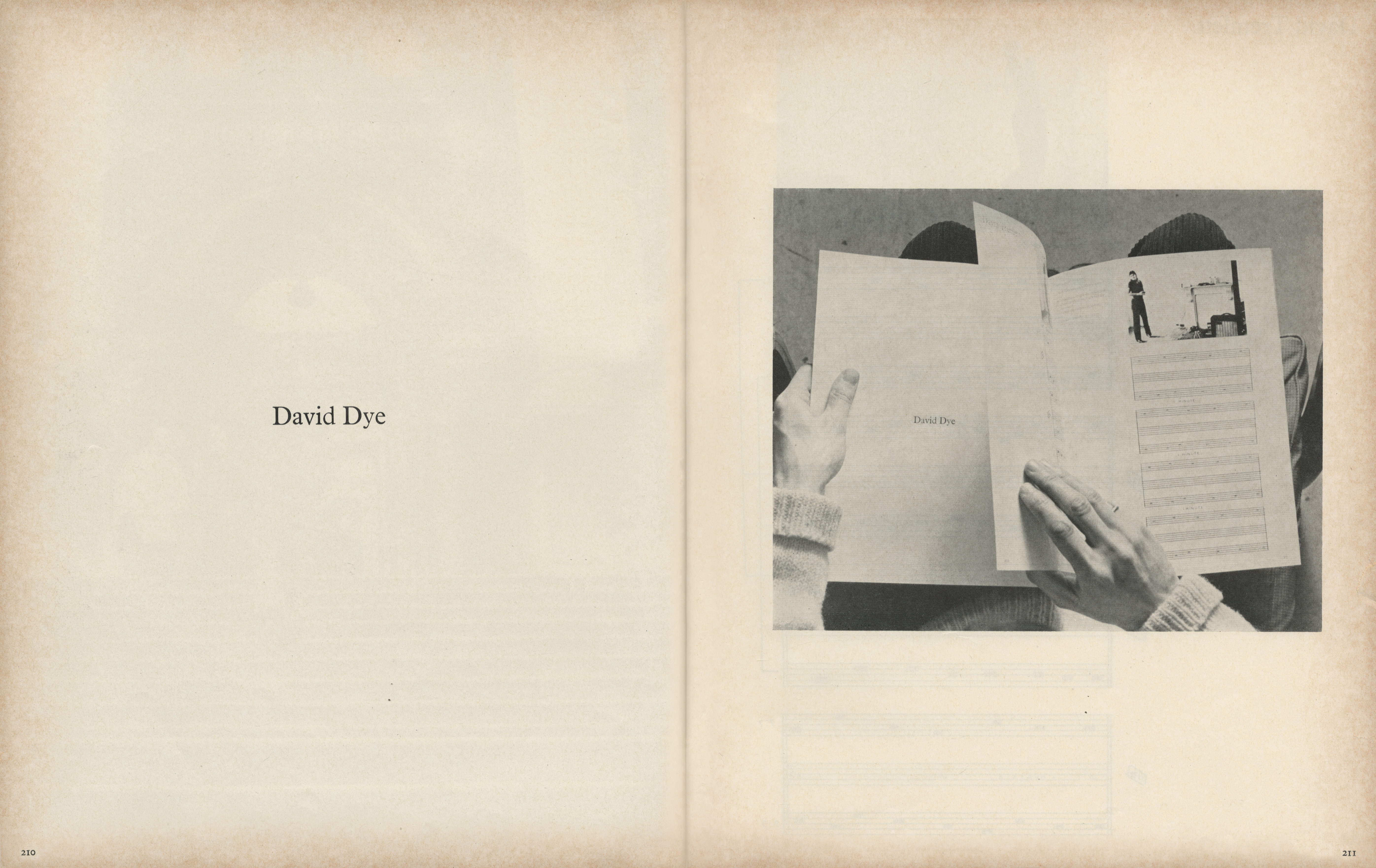 Pages of a magazine. In a black and white photograph on the right, we look down onto a book, this book, held on a man’s lap. His hands turn the page, this page, to show the following spread.