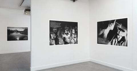 Installation photograph. Three black and white images are affixed to a gallery wall. White text is printed in a corner of each.