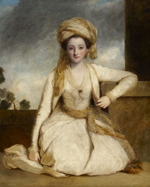 Painting. Portrait of a pale-skinned woman sitting on her knees in front of a ledge under a cloudy sky. She looks at us with hooded, dark eyes. She wears a gold-coloured turban and sash around her waist, over an ivory-white dress.