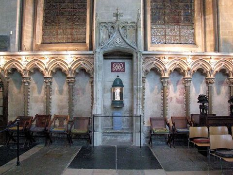 Choir screen. Colour photograph of a stone structure set against a stone wall so the tri-lobed arches appear filled in. The columns are lined with flame-like ornaments.