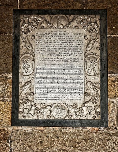 Black and white photograph. We look down onto a nave, which is packed with people. Text is printed in white against black above and below.