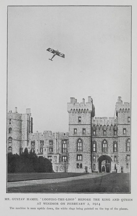 Black and white photograph. An airplane appears to fly almost straight up over a stone castle. White rings are painted on the wings. Text under the image reads, “Mr. Gustav Hamel ‘Looping-the-Loop' before the King and Queen at Windsor on February 2, 1914 The machine is seen upside down, the white rings being painted on the top of the plane”.