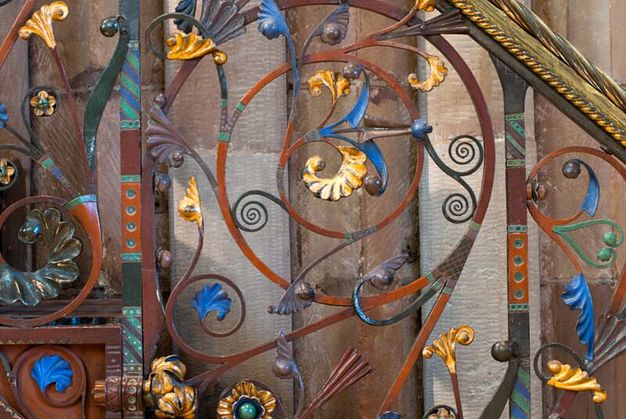Railing. Curling, swirling ironwork is gold-coloured or painted brilliant blue, muted purple, pine green, or umber orange.