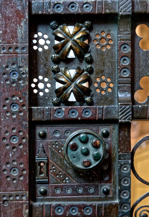 Metalwork. Detail view of an iron gate lock, which is punched and pierced with geometric designs and set with stones.
