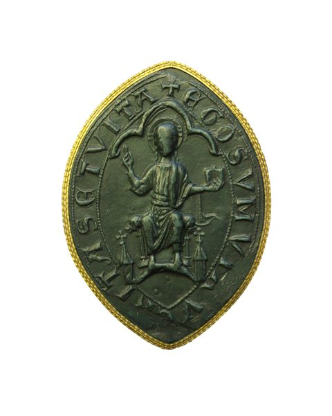 Seal. Cast of a marquise-shaped seal shows a seated man, Christ in Judgment, with both hands raised, one holding a book. He is under a three-lobed arch. Text around the perimeter is partially lost due to damage around the bottom edges. Remaining Latin text reads, “TA SETVITA EGO SVM V”.