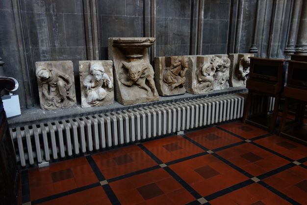 Architectural features. Carved from stone, men and women stoop or twist against flat backgrounds in these six corbels, which are displayed on a long window ledge inside a church.
