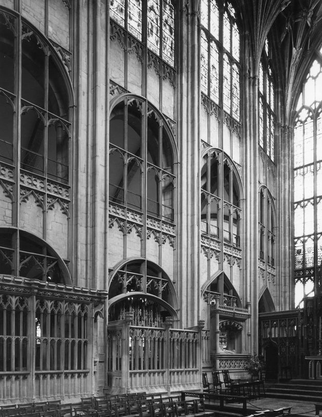 Architecture. Black and white photograph of a web of tracery with pointed arches and leafy patterns overlaid on two levels of rounded arches and a third storey of round-topped stained glass windows.