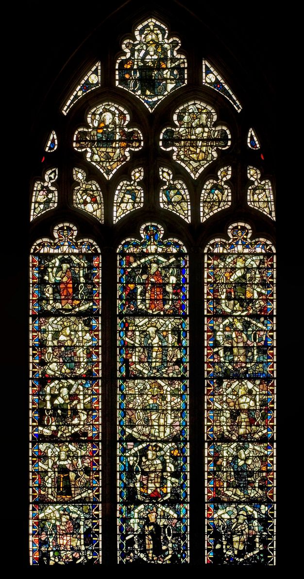 Stained glass window. Three columns of stained glass windows are set within an encompassing arch. The details of the people and objects shown in the glass are difficult to make out in this image.