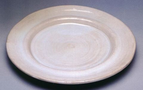 Plate. This white, earthenware plate has a slightly concave rim around a flat, round centre.