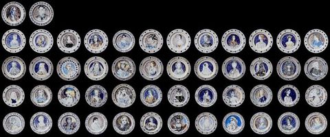 Plates. Fifty plates are arranged against a black background. Each is painted with a portrait of a women. The plates are arranged in a grid of twelve across and four down, plus two additional plates at the upper left.