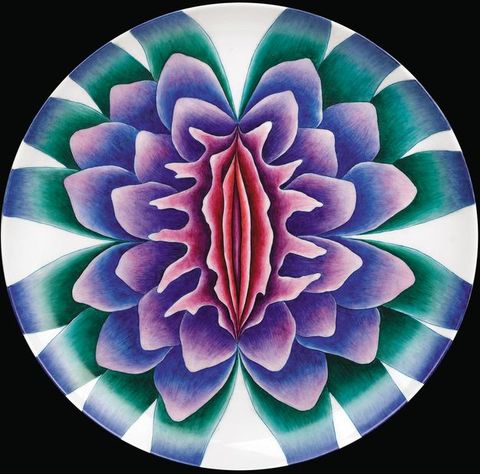 Plate. A flower is painted in jewel-like tones of pink, blue, purple and green. The central petals are vertical, narrow and pink and they become more rounded as they move out.