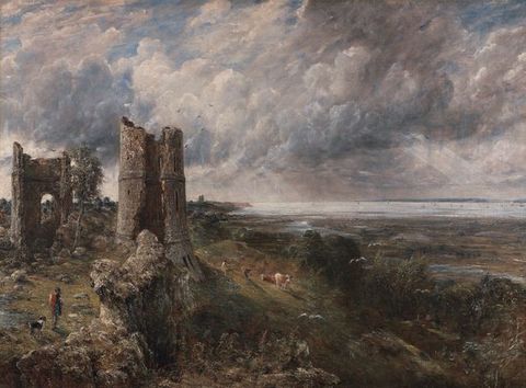 Painting. The ruins of a building and its tower, to our left, perch at the edge of a slope that leads down to a low plane and then to a wide expanse of water to our right. A person and dog walk near the lower left corner of the canvas, and another person tends three cows near the tower. The horizon comes just under halfway up the composition. Rays of sunlight angle down out of pale grey, blue, and white clouds above.