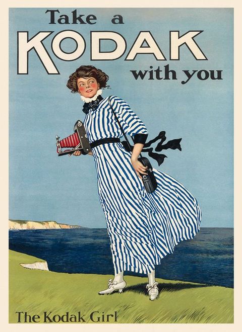 Ad. A pale-skinned woman wearing a long dress with a high, ruffled neck stands near a cliff edge overlooking the sea, a telescoping camera held in one hand. Text across the top reads, “Take a Kodak with you”.