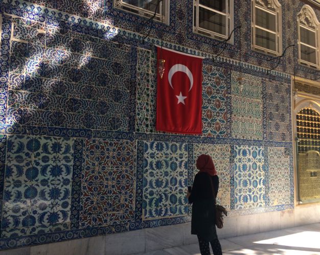 Architecture. Panels of intricately patterned tiles in mostly blue with touches of green, red, or yellow fill this wall.