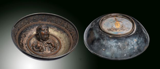 Vessel. Two views of a metal bowl. Inside, a three-dimensional figure, baby Hercules, grips two snakes. The other view shows the oxidized underside of the bowl.