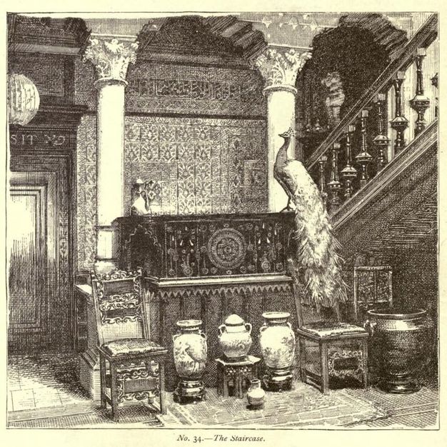 Illustration. Porcelains and a stuffed peacock are arranged in front of and on a low wall leading to a staircase with heavily carved spindles. Columns hold up a panelled ceiling, and the wall behind is covered with patterned paper or cloth.