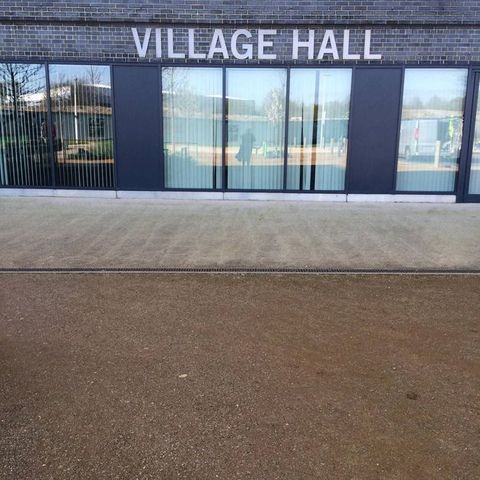 Architecture. A long building with the sign “Village Hall” is above a bank of windows.