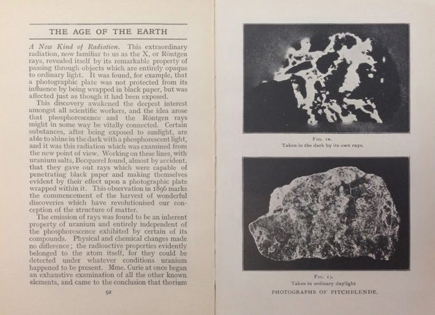 Book spread. The page of text to our left is headed “The Age of the Earth”. Two illustrations on the right page are labelled “Photographs of Pitchblende”. Both show a rock against a dark background. The top image is stark black with vivid white lines and is captioned, “Fig 12. Taken in the dark by its own rays”. The image below is less contrasted and captioned “Fig. 13. Taken in ordinary daylight”.