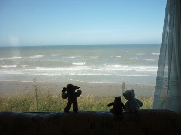 From the beach, we look up a sheer cliff face at shallowly peaked rooflines of caravans poke up over the edge.