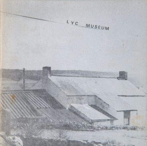 Book cover. Faded, black and white photograph of rooftops and a white-sided house. The angled title looks like it is underlined by a powerline.
