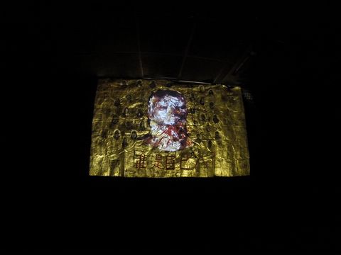Video gif. Red lines spatter from a face shown against a gold field.