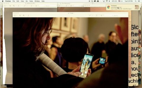 Screenshot. An image of a person taking a picture in an art gallery is at the front of windows layered on a computer desktop. The person looks at his phone, finger poised to take the picture, which is of a woman wearing a yellow suit and reading from a piece of paper.