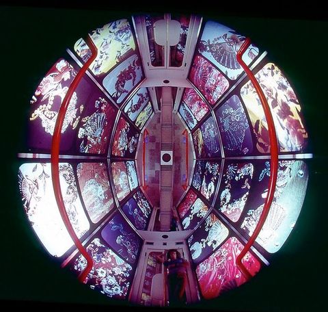 Installation. A round, disorienting space is given some direction when we find a person standing at double doors at the bottom centre of the circle. This suggests we look up into a space from under a glass floor. The walls are covered with floral and decorative patterns.