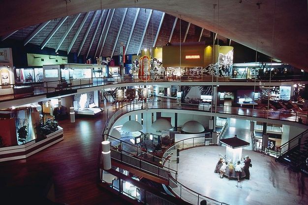 Installation. The topmost of three levels around an open space is lined with colourful exhibits.
