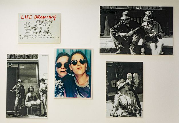 Installation. Three black and white photographs, a colour snapshot as from a photo booth, and a drawing are displayed against a white background.