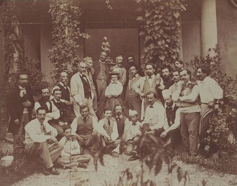 Black and white photograph. A woman is surrounded by twenty-four men in a courtyard.