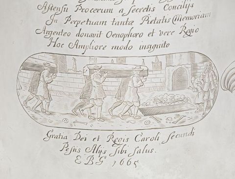 Tankard. Detail view of an oval shaped cartouche and text incised on its surface. In the cartouche, four men carry a casket on their shoulders as they walk towards an open grave surrounded by skulls and bones. Another foursome follows behind them.