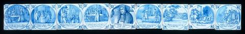 Tiles. Nine tiles painted blue against white show groups of people or, for the one in the centre, a portrait of a single person. Details in the pictures and writing under each are difficult to make out in this image.