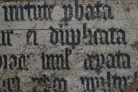 Painting. Detail view of black letters along dark incised guidelines incised into the white ground.