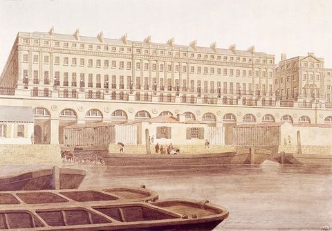 Watercolour/drawing[??]. Across a river, four levels with thirty-three windows each line long, rectangular building. A row of arches below and in front of the building is partially hidden by a structure on the dock.