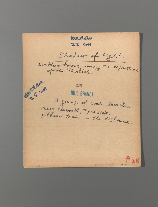 The back of a photograph has dimensions written at the top and sides, reading “22 cm” and “25 cm”, respectively. Handwriting reads, “Shadow of Light. Northern towns during the depression of the ‘thirties” above the photograph’s title, also written in pen.