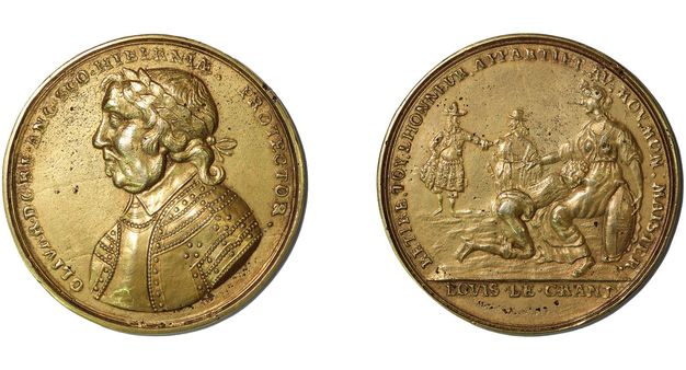 Medal. On the recto of a gold medal, a man with sagging jowls and a double chin is shown in profile facing our left. Armour covers his chest and shoulders, and he wears a crown of laurels. On the verso, to our left, a man kneels, bare-buttocked, with his head in the lap of a woman. Two people stand in the distance. Text is in relief around both sides of the medal.