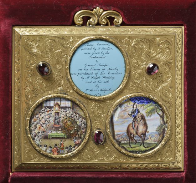 Two round enamelled paintings are set into a gilded frame incised with curlicues and leafy patterns. One enamel shows people gathered in a meeting chamber and the other a man on horseback. A third, round opening contains text. Three purple jewels are set into the gold.
