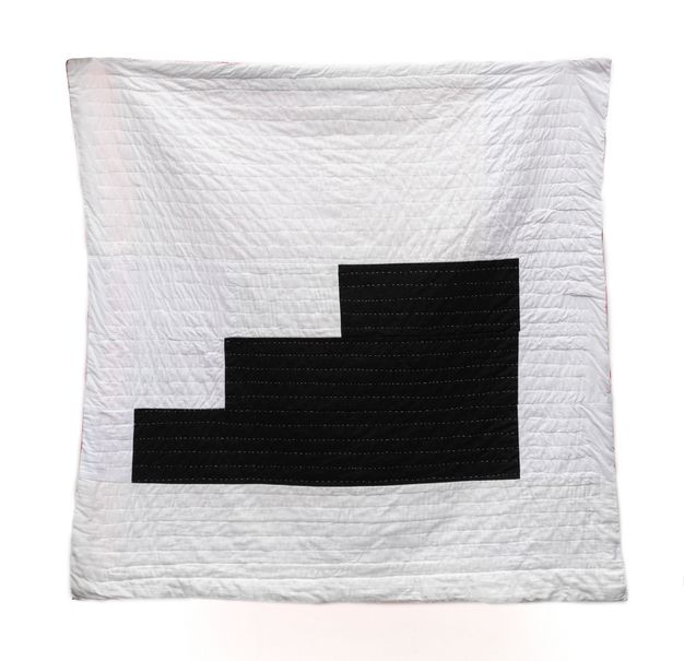 Quilt. A black silhouette of three steps rising to our right is against a white square. Horizontal stitching creates rows against both colours